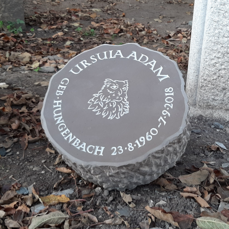 Runde Grabplatte in Baumscheibenform mit genutetem Eulen-Motiv  und im Kreis angeordneter Römischer Kapitalschrift aus Bergischer  Grauwacke