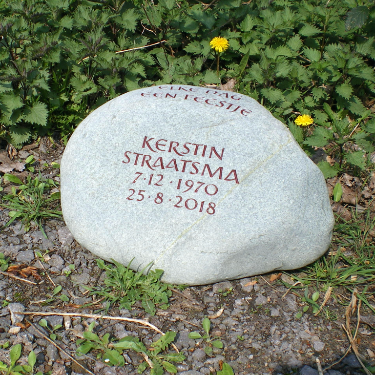 Grünlicher Grabstein-Findling für ein Baumgrab mit tief eingravierter, rötlich getönter Inschrift