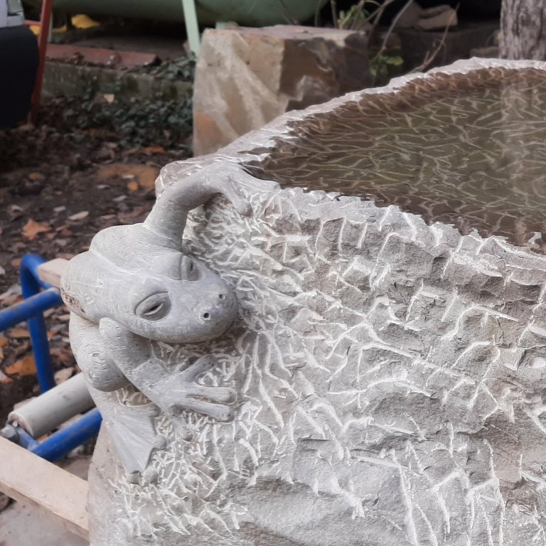 Vogeltränke aus Bergischer Grauwacke mit  vollplastisch gearbeiteter Frosch-Skulptur, zu  sehen auf dem Nordfriedhof in Köln