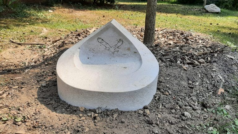 Handwerklich bearbeiteter Grabstein in runder Form mit Überdachung  und genutetem Adler-Ornament