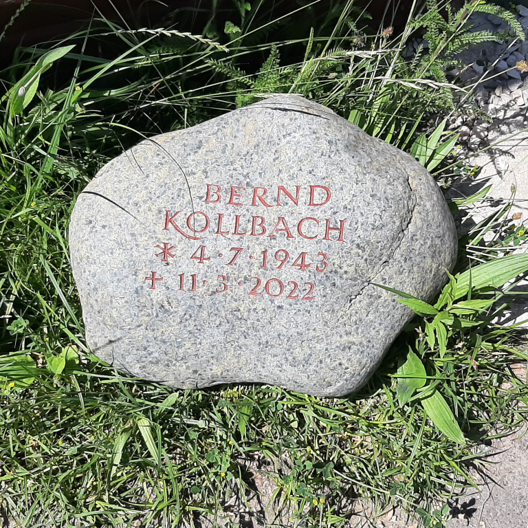 Beschrifteter Grabstein-Findling, integriert in ihn umgebende  Bepflanzung