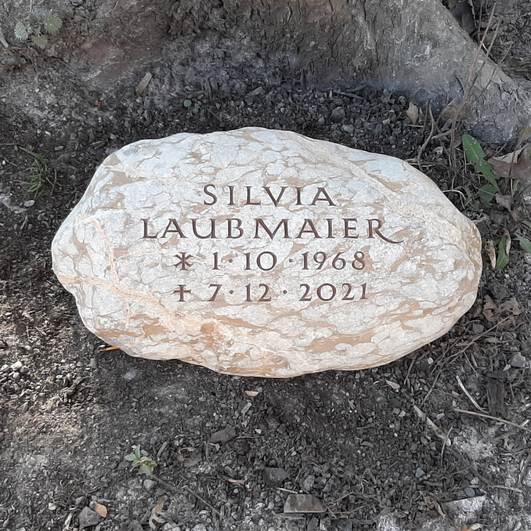 Beige marmorierter, weißer Findling-Grabstein, mit  eingravierter,braun getönter Kapitalis-Beschriftung