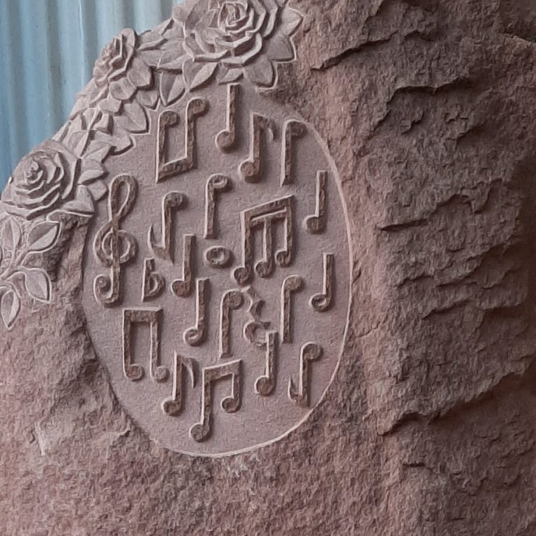 Plastisches Rosen-Ornament und erhabene Musik-Noten in rotem Eifel-Sandstein