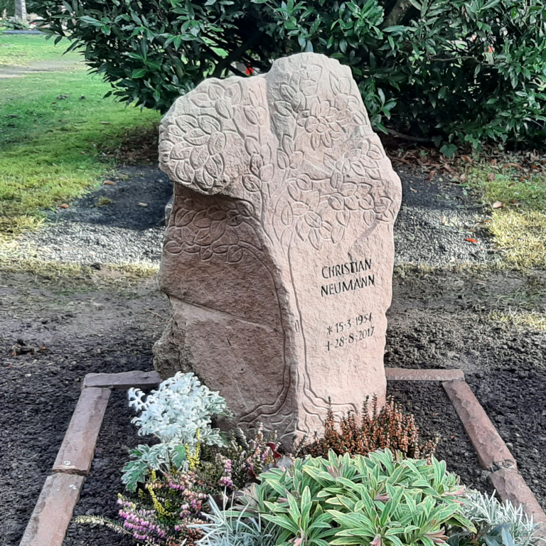 Urnen-Grabstele aus natürlich gebrochenem Kylltaler Sandstein mit Baum-Ornament und tief eingehauener Inschrift, umgeben von einer passenden Einfassung
