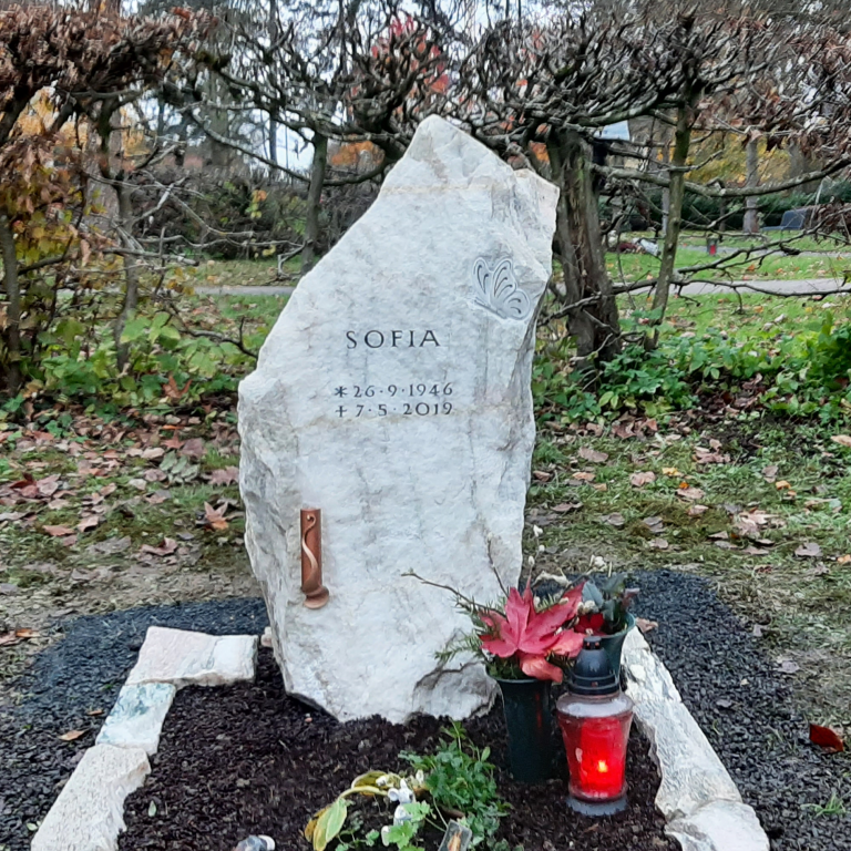 Felsen-Grabstein aus Sölker Marmor mit Schmetterlings-Ornament und Grabeinfassung aus unregelmäßigen Mauersteinen