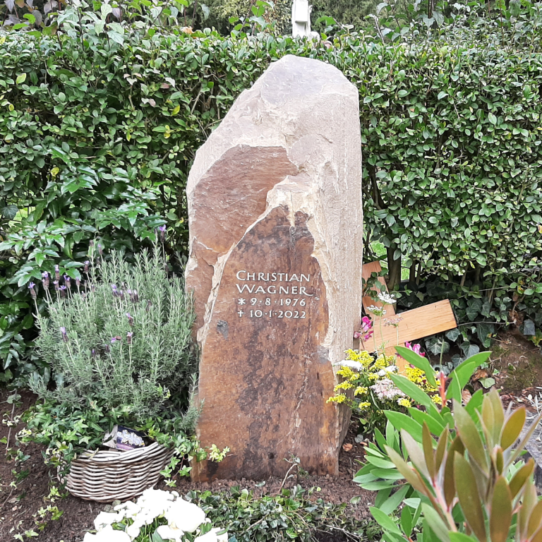 Grabstein-Felsen mit natürlich gebrochenen, versetzten Vorderflächen und tief eingravierter, hell getönter Beschriftung