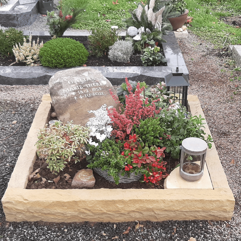 Urnengrab mit Bräunlichem Grabstein-Findling aus einer Brekzie, mit eingehauener Schrift und einer Einfassung aus Baumberger Sandstein