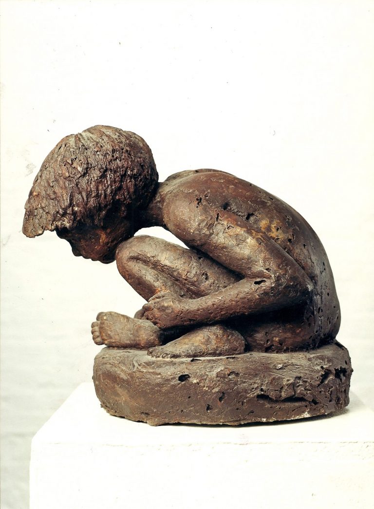 Ansicht von links einer Skulptur aus Polyesther,  die einen sitzenden Jungen in gebeugter Haltung darstellt, der seinen rechten Fuß anschaut