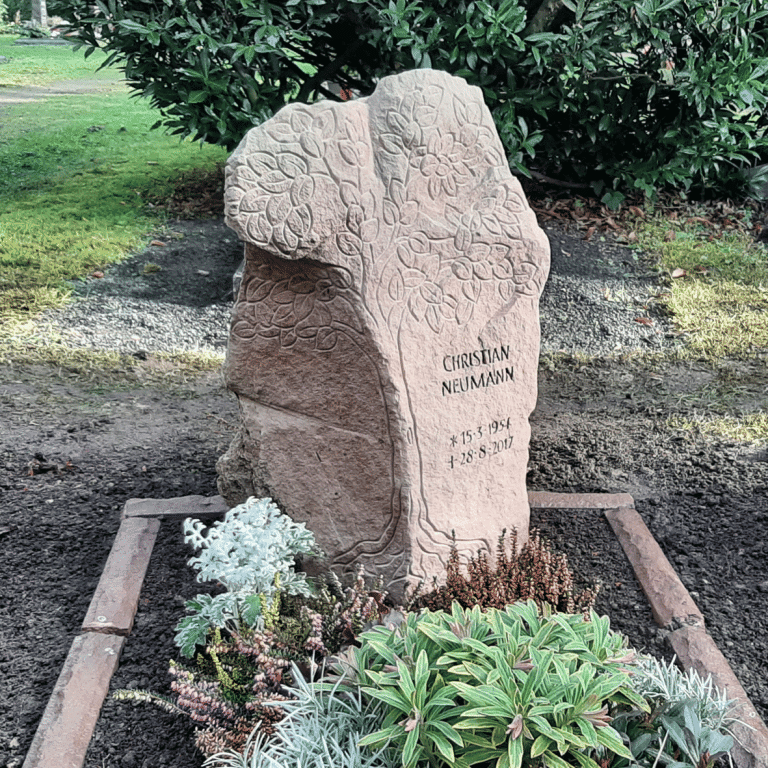 Urnen-Grabstele aus natürlich gebrochenem Kylltaler Sandstein mit Baum-Ornament und tief eingehauener Inschrift, umgeben von einer passenden Einfassung