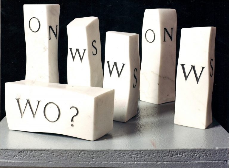 Gruppe von Miniatur-Stelen aus Carrara-Marmor, die auf ihren vier Flächen die Anfangsbuchstaben der Himmelsrichtungen eingraviert haben