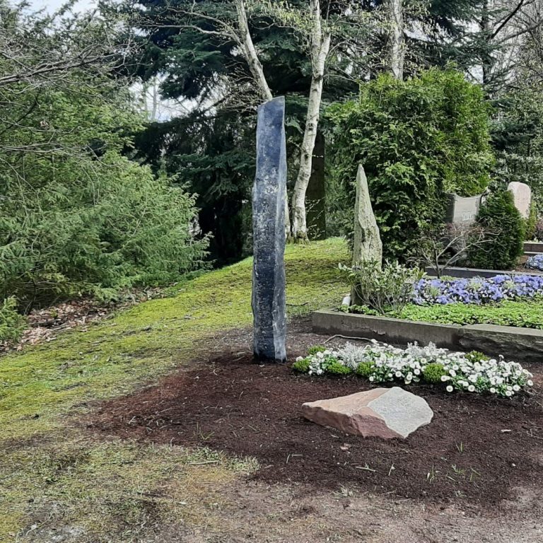 Grabmal-Stele aus Basaltsäule mit davor liegendem, beschriftetem Grabstein aus Ruhr-Sandstein